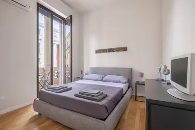 a bedroom with a bed and a tv and a desk at Ninni's House by DomuSicily in Palermo