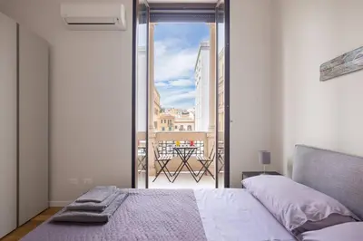 a bedroom with a bed and a view of a balcony at Ninni's House by DomuSicily in Palermo