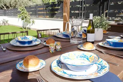 a wooden table with blue and white plates and a bottle of wine at Villa Rosina in Cinisi