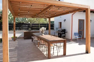 a wooden pergola with a table and chairs on a patio at Villa Rosina in Cinisi