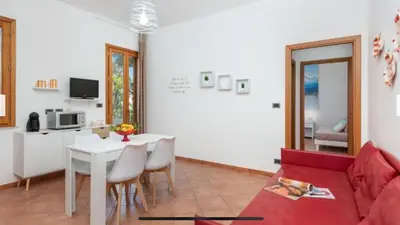 a living room with a red couch and a table at Blue Coral in San Vito lo Capo