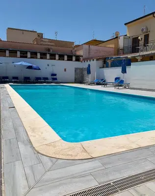 a swimming pool with blue water in front of a building at Blue Coral in San Vito lo Capo