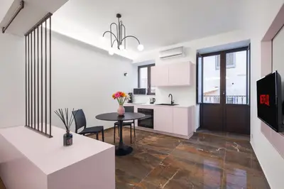 a white kitchen with a table and a counter at A Casa di Giulia - elegante loft in centro storico in Palermo