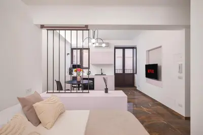 a white living room with a bed and a kitchen at A Casa di Giulia - elegante loft in centro storico in Palermo