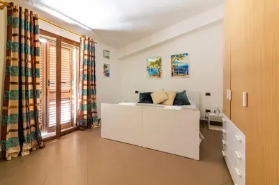 a white bedroom with a bed and a cabinet at Kanisa Mari e Monti in Cinisi