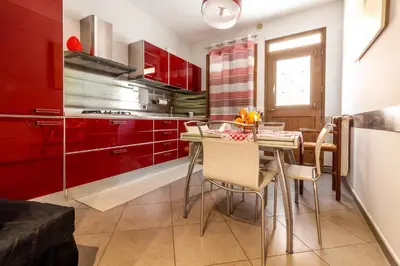 a kitchen with red cabinets and a table with chairs at Kanisa Mari e Monti in Cinisi