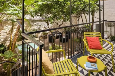 a balcony with two chairs and a table with a red pillow at The Garden Boutique Apartment by DomuSicily in Palermo