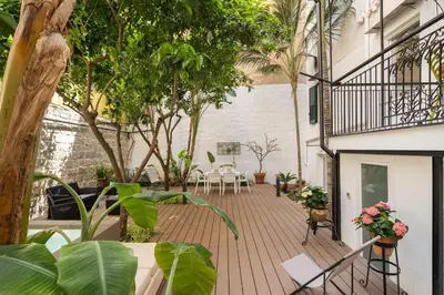 an outdoor patio with tables and chairs and trees at The Garden Boutique Apartment by DomuSicily in Palermo