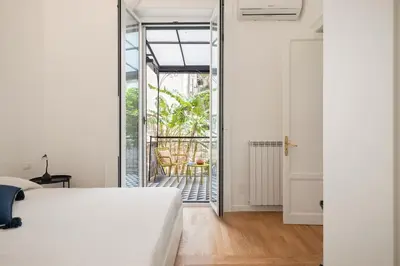 a bedroom with a white bed and a sliding glass door at The Garden Boutique Apartment by DomuSicily in Palermo