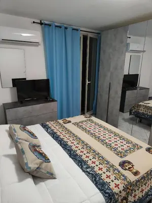 a bedroom with two beds and a television and blue curtains at Casa Josè Suite Mare in Palermo