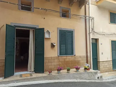 a building with green shutters and flowers on the doorstep at La Casetta di Marianne in Santa Flavia