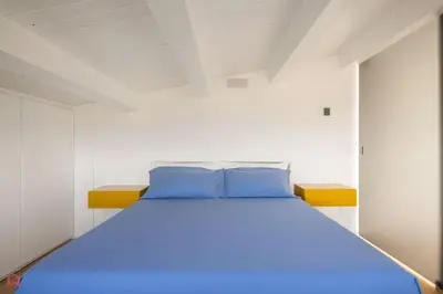 a bed with blue pillows in a white room at Sea View Villa whit Pool in Scopello