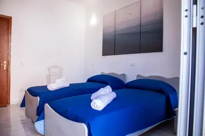 two beds in a room with blue sheets at Casa vacanze Rigano Palermo in Palermo