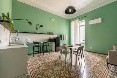 a kitchen with green walls and a table and chairs at Stylish apartment near Piazza Magione by Wonderful Italy in Palermo