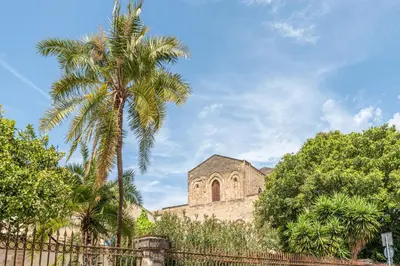 a church with a palm tree in front of a fence at Stylish apartment near Piazza Magione by Wonderful Italy in Palermo