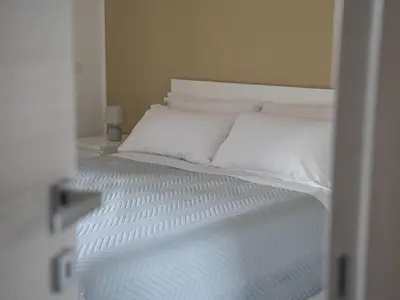 a bed with white sheets and pillows in a room at Central Station Home - Fanale Rentals in Palermo