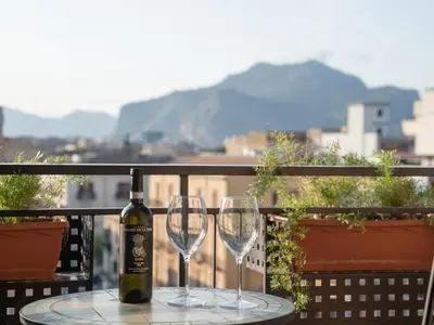 a bottle of wine sitting on a table with two glasses at Central Station Home - Fanale Rentals in Palermo