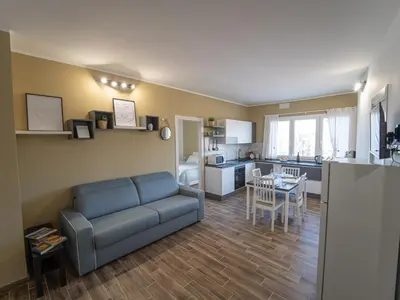 a living room with a blue couch and a kitchen at Central Station Home - Fanale Rentals in Palermo