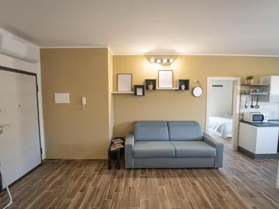 a living room with a blue couch and a kitchen at Central Station Home - Fanale Rentals in Palermo