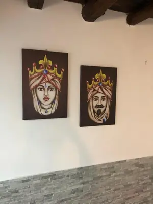 two paintings of a woman wearing crowns on a wall at La casetta del borgo in Palermo
