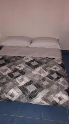 a bed with a black and white comforter on it at Case Billeci Casa blu in Palermo