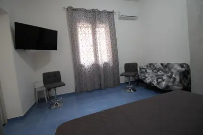 a bedroom with a bed and two chairs and a television at Case Billeci Casa blu in Palermo