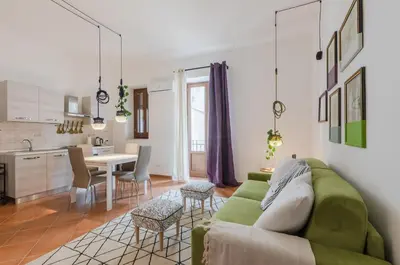 a living room with a green couch and a kitchen at GuestHost - Ballarò Cozy Apartment with Balconies in Palermo