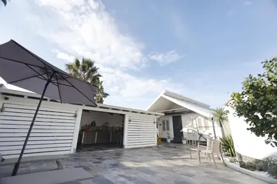 a white house with a patio and an umbrella at Al Cottage Isola Delle Femmine in Isola delle Femmine