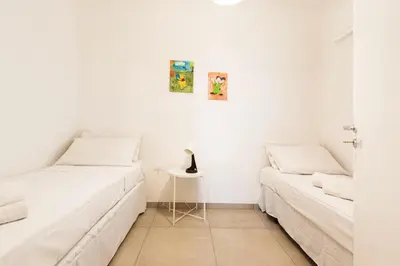 a white room with two beds and a table at Visitsicilia Rosetta Mare in Alcamo Marina