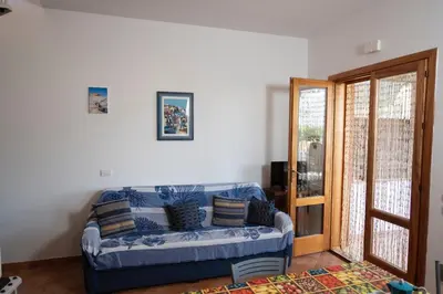 a living room with a blue couch in front of a door at Casa Sally con Vista Mare a Macari in Macari