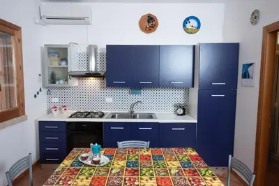 a kitchen with a table with a sink and blue cabinets at Casa Sally con Vista Mare a Macari in Macari
