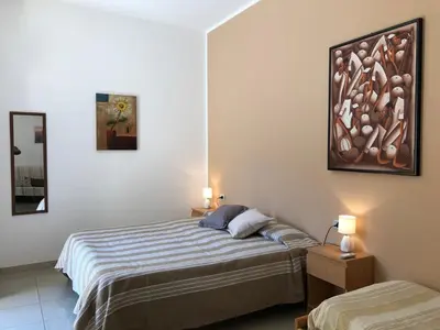 a bedroom with two beds and a painting on the wall at Villa Gelvi in Castellammare del Golfo