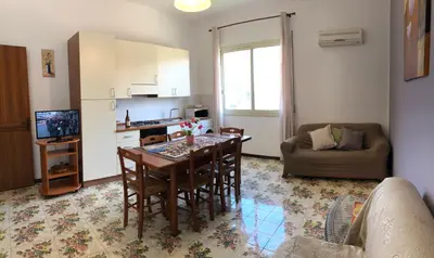 a living room with a kitchen and a dining room table at Villa Gelvi in Castellammare del Golfo