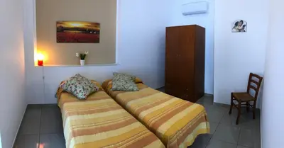 a bedroom with two twin beds and a chair at Villa Gelvi in Castellammare del Golfo