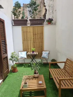 a patio with chairs and a table and some plants at Giardino Moreno in Palermo