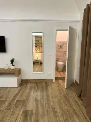 an empty living room with wooden floors and a mirror at Il Moro in Carini