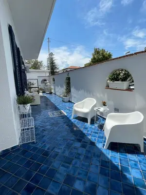 a patio with white chairs and a blue tile floor at The k house in Palermo