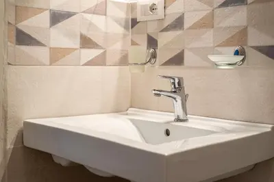 a white sink in a bathroom with a tiled wall at LA VECCHIA PALERMO in Palermo
