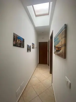 a hallway with three paintings on the wall and a skylight at Quattrociocchi apartment in Bagheria