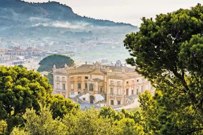 a view of a mansion with trees in the foreground at La Dimora di David in Bagheria