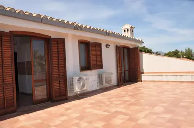 a house with wooden doors and a patio at Villa Cala Rossa Antonella in Castellammare del Golfo