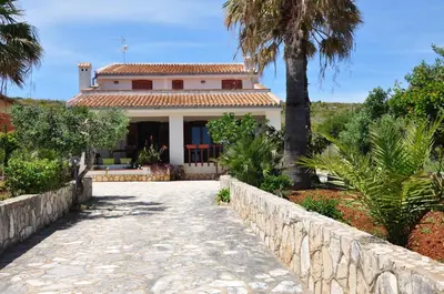 a house with a stone walkway in front of it at Villa Cala Rossa Antonella in Castellammare del Golfo