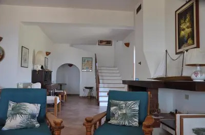 a living room with blue chairs and a staircase at Villa Cala Rossa Antonella in Castellammare del Golfo