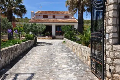 a driveway leading to a house with a fence at Villa Cala Rossa Antonella in Castellammare del Golfo