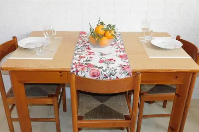 a wooden table with two chairs and a tablecloth with fruit on it at - Palermo - Sferracavallo sul mare in Palermo