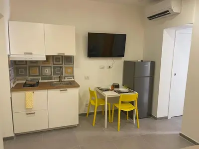 a kitchen with yellow chairs and a table and a refrigerator at Amunì o 123 in Palermo