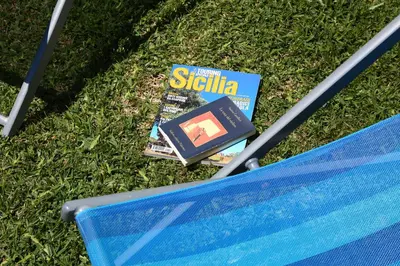 a book sitting on the grass next to a bench at verdemare in relax in Cefalù