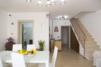 a white dining room with a white table and stairs at B&B Piano di Sopra in San Vito lo Capo