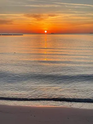 a sunset on the beach with the sun setting over the water at Villa Mondello Terraces & Jacuzzi in Mondello