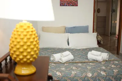a bedroom with a bed with towels and a chair at Colonna House Casa vacanze tra la Zisa e la Cattedrale in Palermo